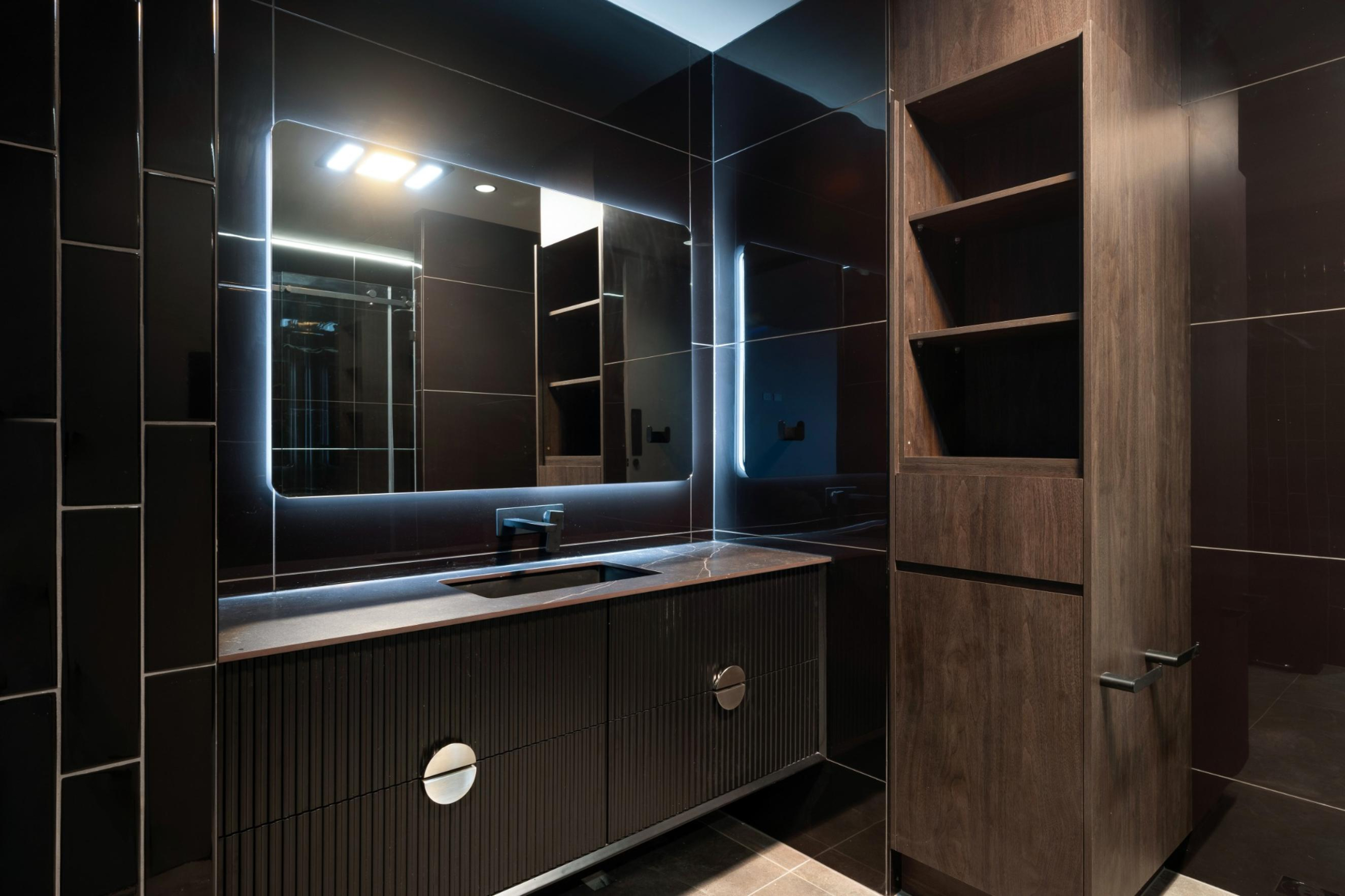 Sophisticated executive ensuite at Infinity Group Australia's Southport office fitout by Leithal Designs, showcasing dark tonal finishes and black tiled feature walls.