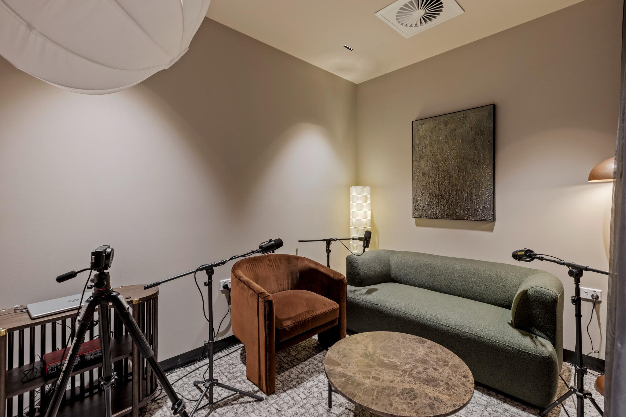 Dedicated podcast room with acoustic treatments and lounge setup – flexible coworking desig
