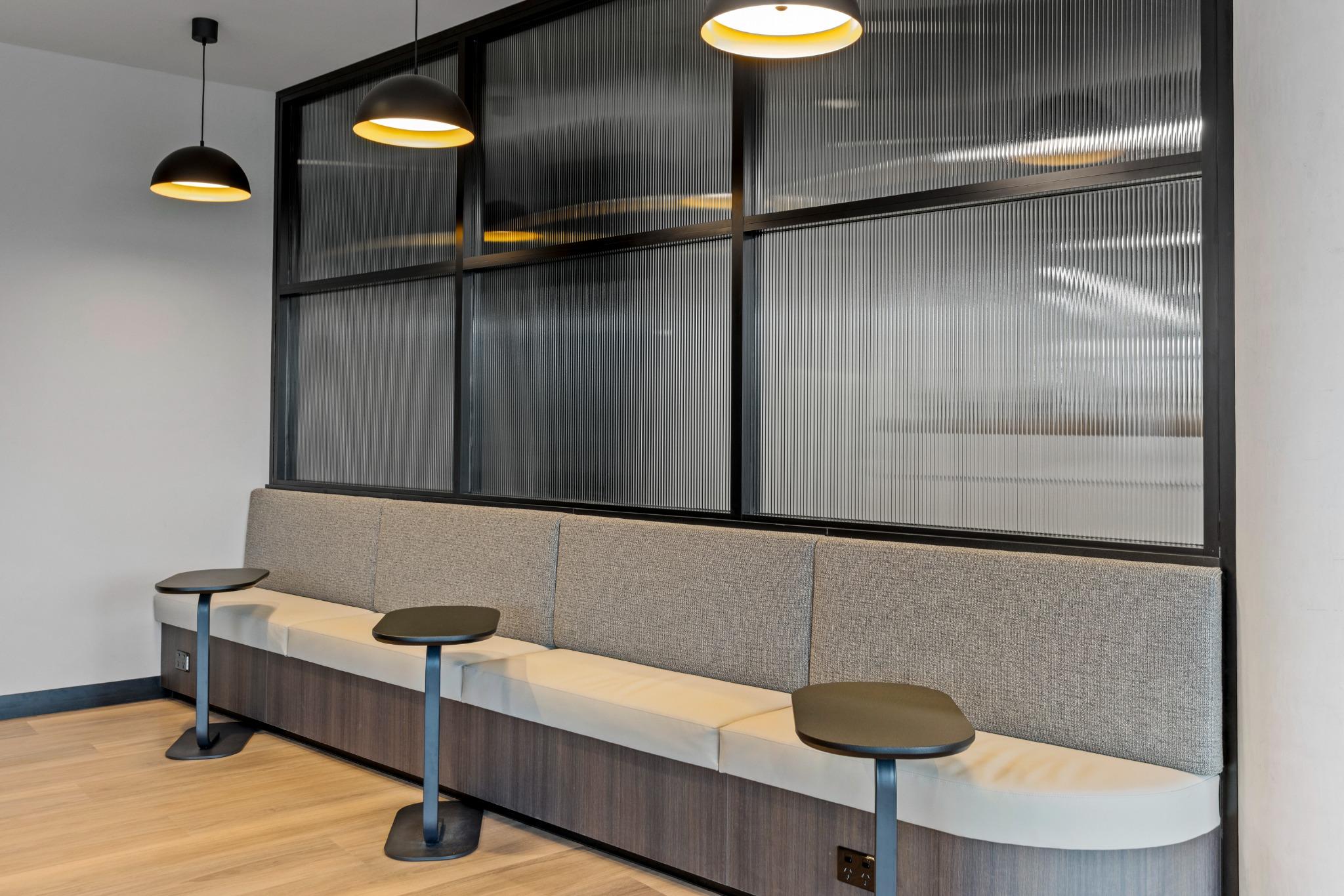 Bench seating with integrated laptop tables and pendant lighting – corporate office breakout zone Robina
