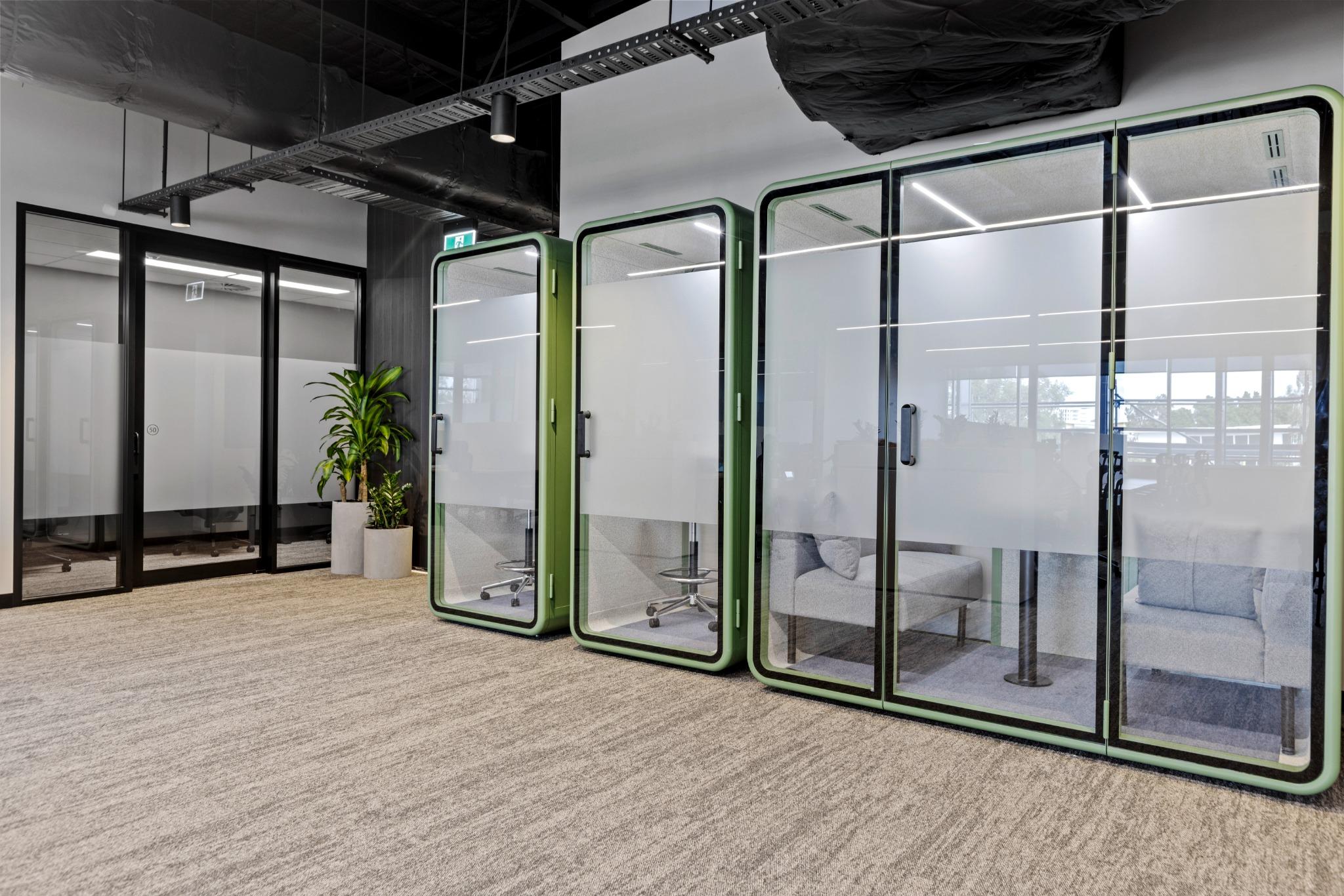 Modern corridor featuring frosted glass office pods and light timber flooring in a commercial office fitout.