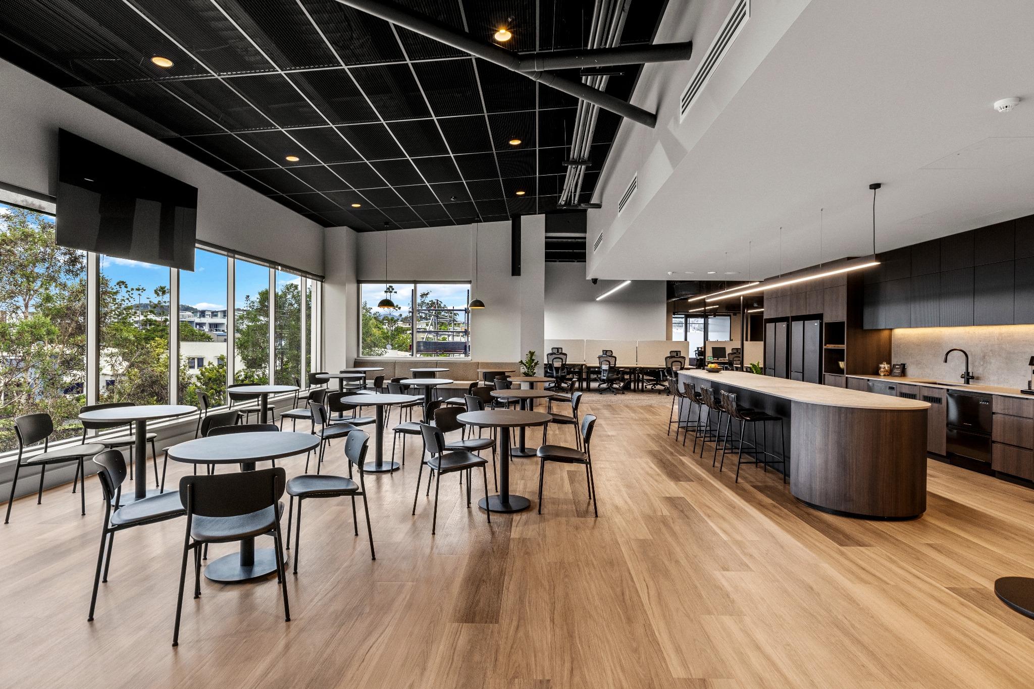 staff kitchenette at Riva Robina featuring black mixer tap, stone-look benchtop, lisurfaces timber-grain joinery, and full-height splashback with integrated open shelving for functional workplace utility.