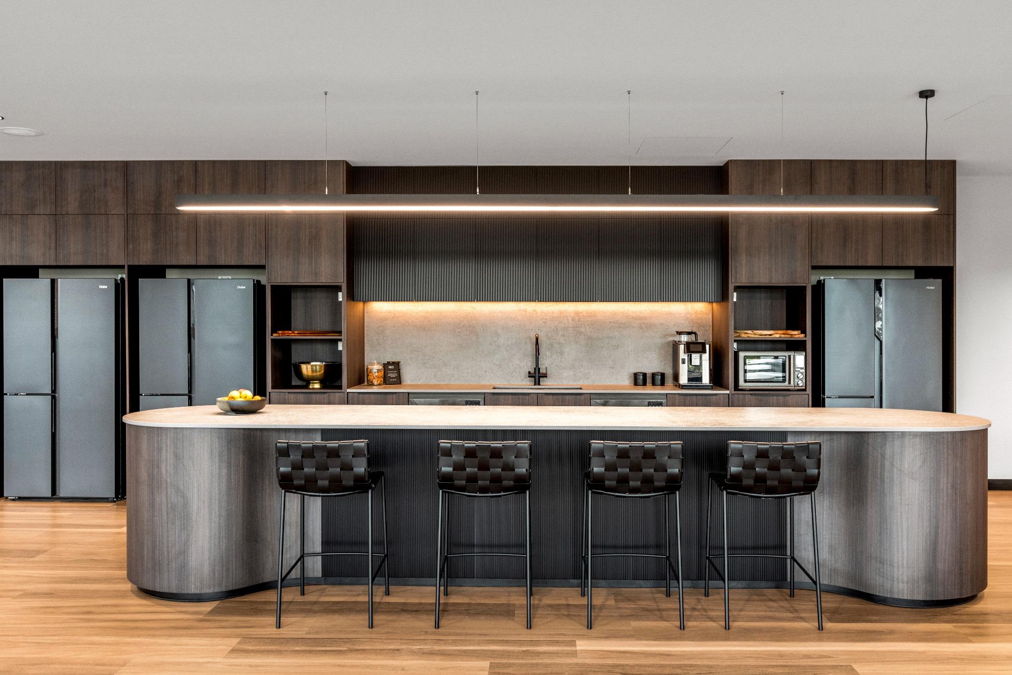 Under-bench lighting and black tapware in a compact kitchenette designed for modern office environments.