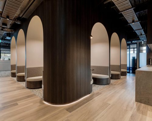 Modern commercial interior featuring arched seating areas and wooden accents, designed for functionality and aesthetic appeal in high-performing workplaces.